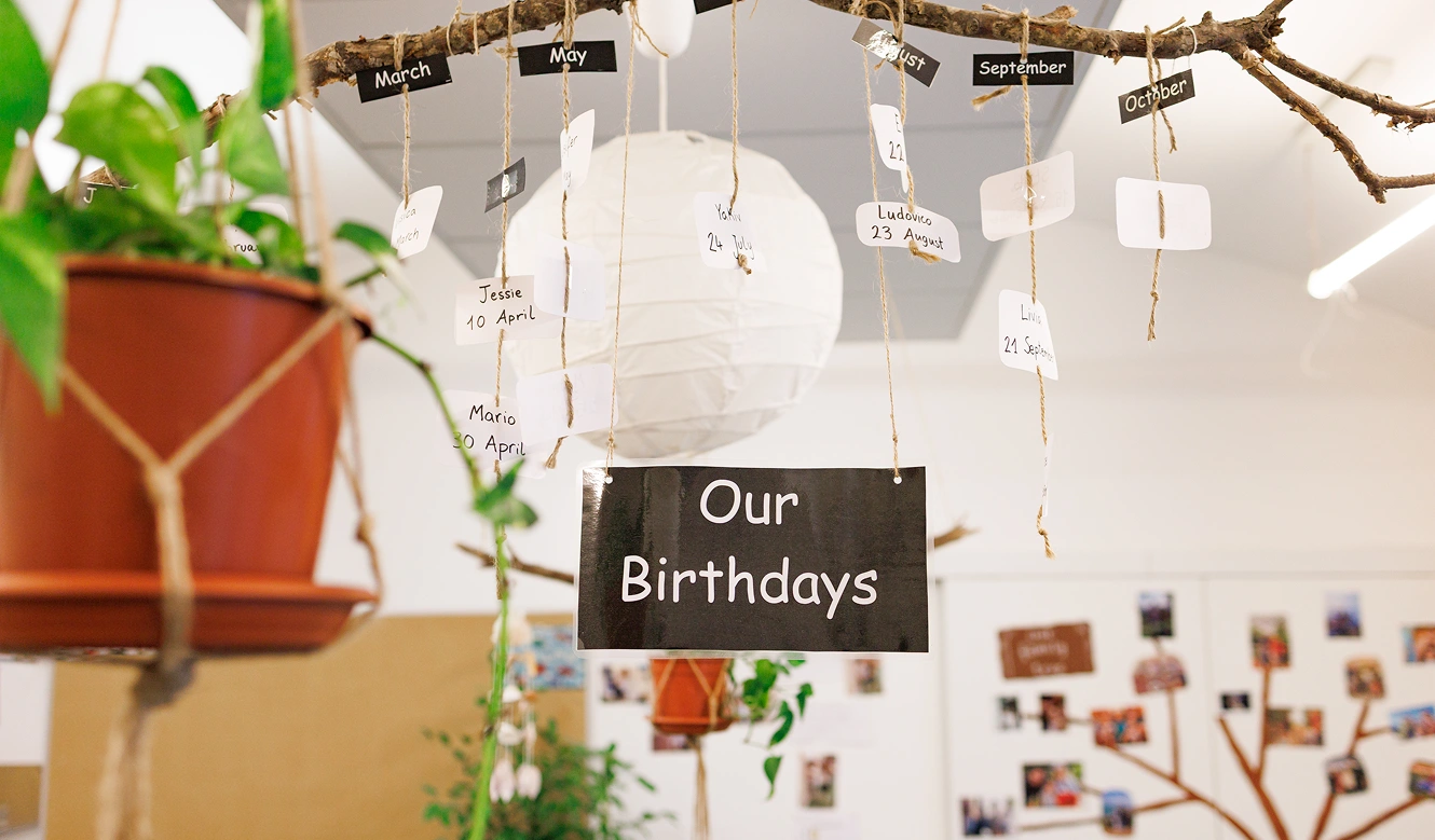 Foto di una composizione intitolata “Our birthdays”: su un ramo sono appese cordicelle corrispondenti ai mesi dell’anno con il nominativo e il giorno di nascita degli alunni