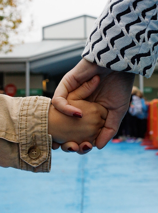 Open day scuole superiori 2025 2026: una mano femminile unita a quella di un bambino lungo un percorso azzurro con transenne colorate