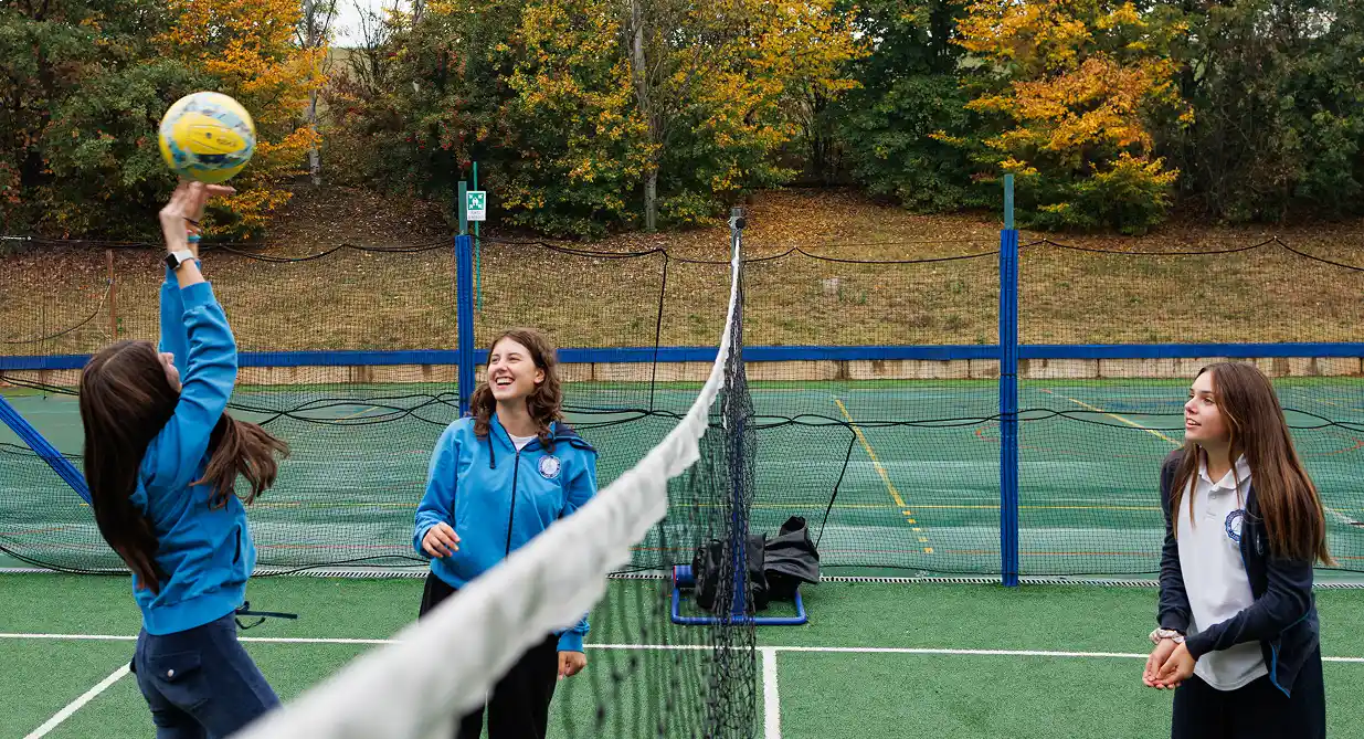 Momento di allenamento per la squadra di volley, uno dei club sportivi scolastici dell’IST. Tre ragazze con la divisa dell’IST palleggiano vicino alla rete